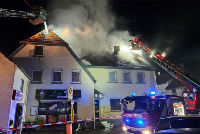 Ein Haus steht in Brand. Die Feuerwehr löscht mit Drehleitern.