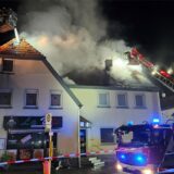 Ein Haus steht in Brand. Die Feuerwehr löscht mit Drehleitern.