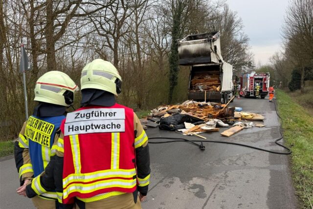 Feuerwehrleute vor einem Müllwagen.