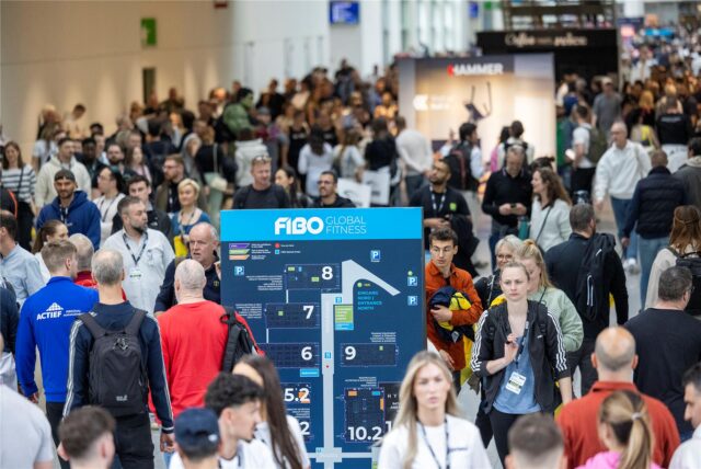 Messebesucher der FIBO laufen in Köln durch eine Messehalle.