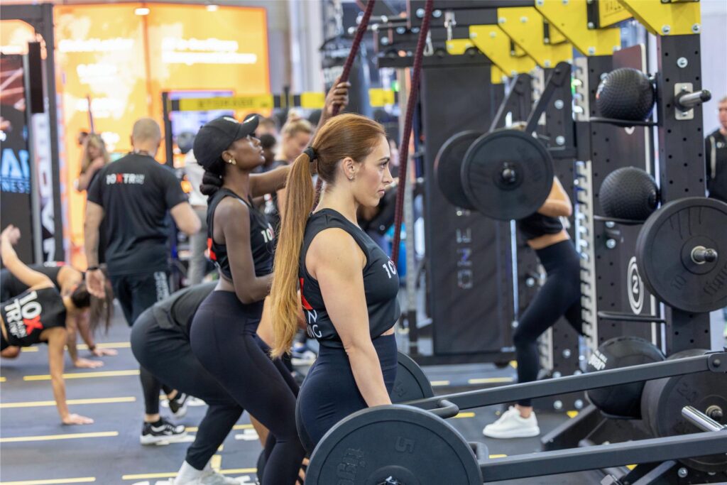 Auf der Fitnessmesse Fibo trainieren Personen an Kraftmaschinen. Auf der Fitnessmesse Fibo trainieren Personen an Kraftmaschinen.