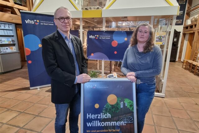 Ein Mann und eine Frau stehen vor VHS-Plakaten.