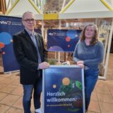 Ein Mann und eine Frau stehen vor VHS-Plakaten.
