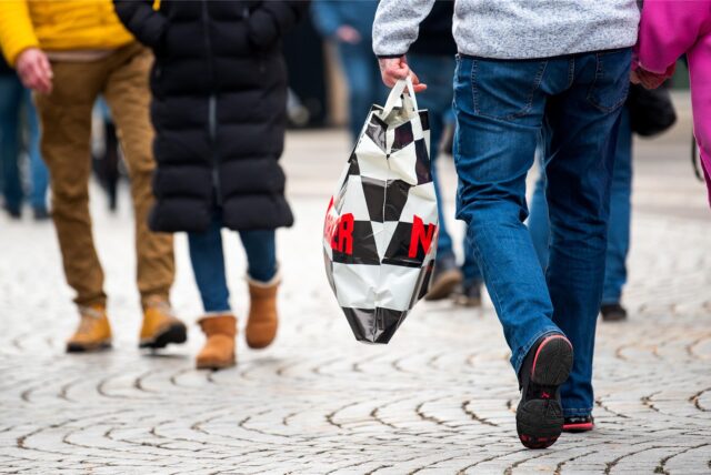 Ein Mann mit einer Einkaufstüte geht während des verkaufsoffenen Sonntags durch die Innenstadt.