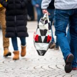 Ein Mann mit einer Einkaufstüte geht während des verkaufsoffenen Sonntags durch die Innenstadt.