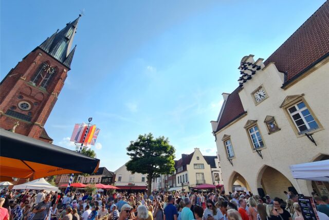 Marktplatz in Haltern bei blauem Himmel mit dem alten Rathaus und der Kirche sowie vielen Menschen und Ständen