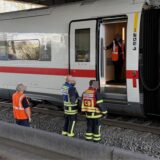 Einsatzkräfte der Feuerwehr stehen neben einem Zugabteil des ICEs, der in Dortmund auf offener Strecke evakuiert werden musste.