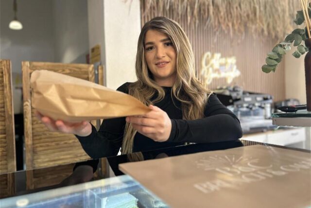 Sibel Cömlek, Inhaberin des Cafés Brunch und Cake in der Hertener Innenstadt, reicht eine Tüte mit Backwaren über die Verkaufstheke.
