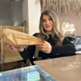 Sibel Cömlek, Inhaberin des Cafés Brunch und Cake in der Hertener Innenstadt, reicht eine Tüte mit Backwaren über die Verkaufstheke.