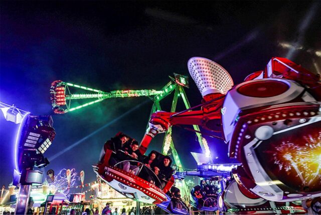 Besucher sitzen auf der Osterkirmes „Fredolino“ 2024 in Dortmund in einem Fahrgeschäft.