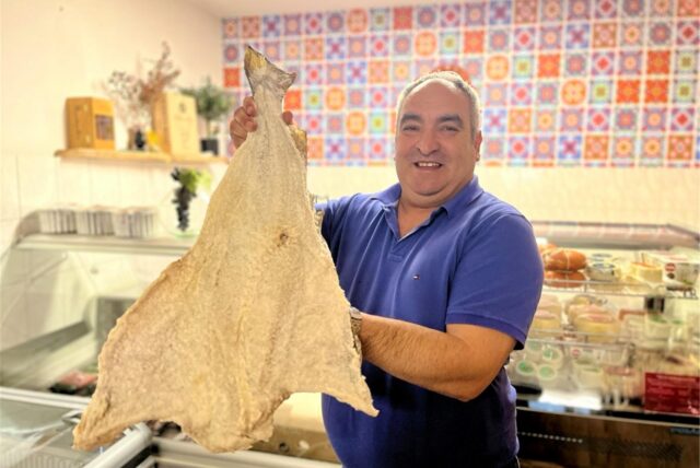 Nelson Marques hält in seinem portugiesischen Supermarkt Olà Portugal in Dortmund einen großen Stockfisch in der Hand.