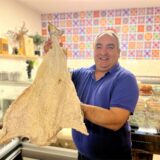 Nelson Marques hält in seinem portugiesischen Supermarkt Olà Portugal in Dortmund einen großen Stockfisch in der Hand.