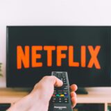Ein Fernseher wird mit einer Fernbedienung angeschaltet und es ist das Netflix-Logo zu sehen.