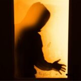Eine menschliche Person steht vor einem Fenster. Es ist nur der Schatten zu sehen.