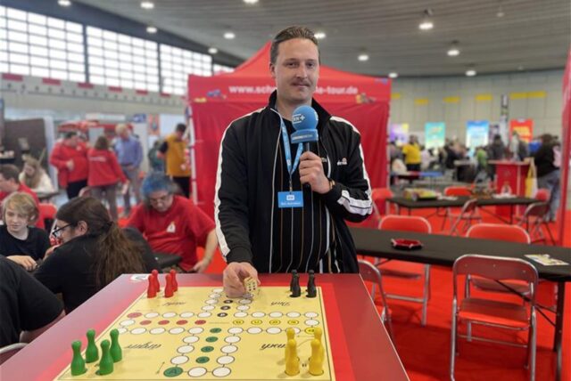 Reporter Tim Hübbertz steht an einem „Mensch ärger dich nicht“-Brett auf der Spielemesse „Spiel doch!“ in Dortmund.
