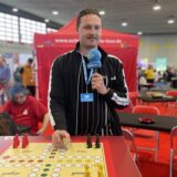 Reporter Tim Hübbertz steht an einem „Mensch ärger dich nicht“-Brett auf der Spielemesse „Spiel doch!“ in Dortmund.