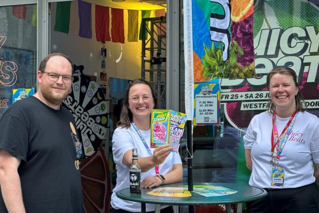Drei Mitarbeitende des Juicy Beats Festivals vor dem Pop-Up-Store in der Hansastraße.