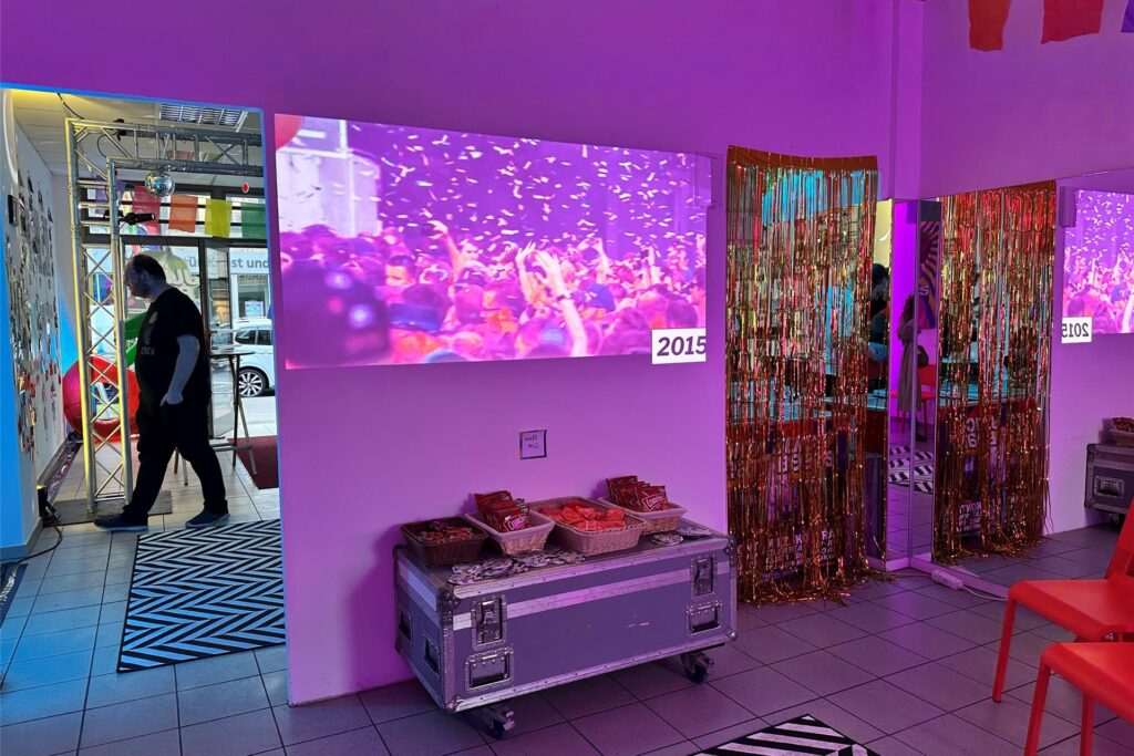 Videos mit Festival-Highlights werden mit einem Projektor auf einer Wand gezeigt.
