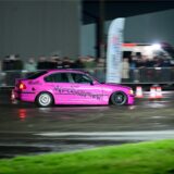 Ein pinker BMW Dreier driftet über den Flugplatz Loemühle. Im Hintergrund sind Zuschauer hinter Absperrungen zu sehen.
