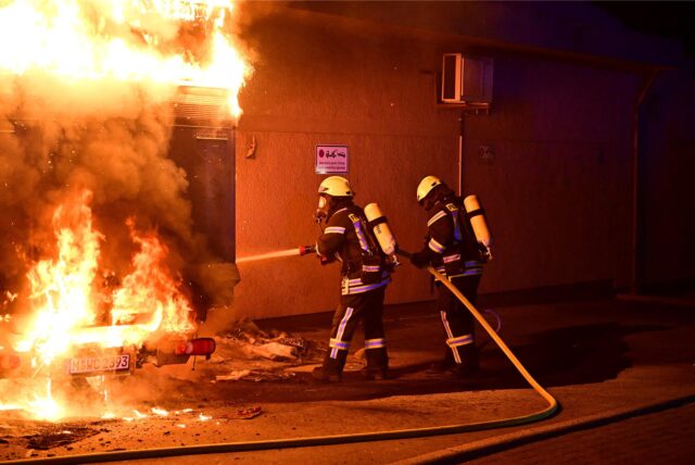 Zwei Feuerwehrmänner löschen ein Feuer an der Kampstraße in Marl.