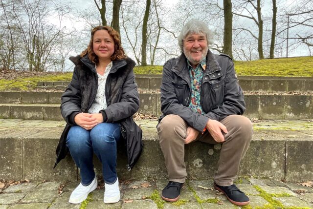 Eine Frau und ein Mann sitzen auf Stufen im Freien.