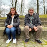 Eine Frau und ein Mann sitzen auf Stufen im Freien.