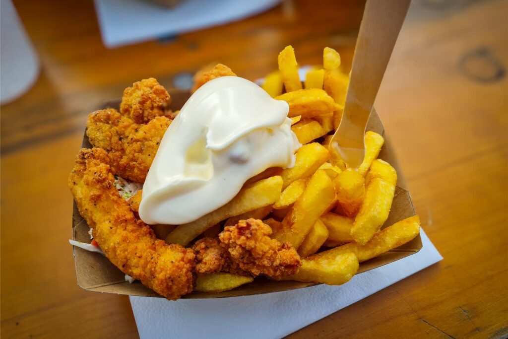 Pommes mit Hähnchen und Mayo in einer Schale auf einem Tisch stehend. Pommes mit Hähnchen und Mayo in einer Schale auf einem Tisch stehend.