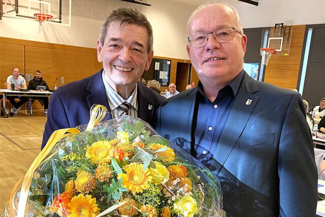 Bürgermeister Werner Arndt überreicht seinem Stellvertreter Michael Bach (r.) einen großen Blumenstrauß.