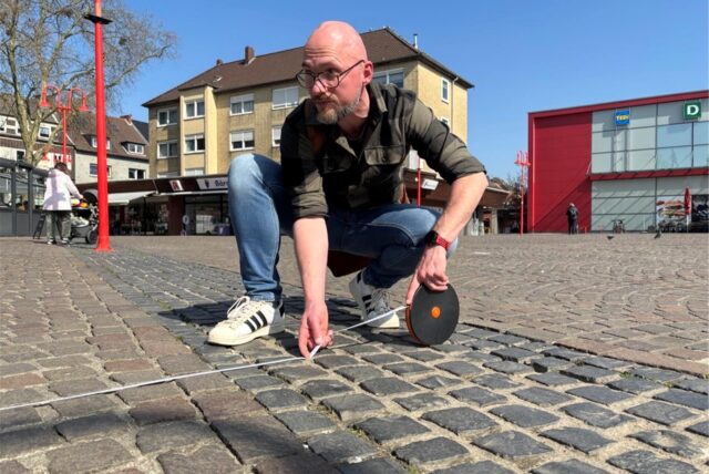 Zwei Männer stehen auf dem Neumarkt in Datteln und halten ein Maßband.