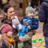 Eine Mutter hat ihren Sohn auf dem Arm und hält ein Esel-Kuscheltier in der Hand.