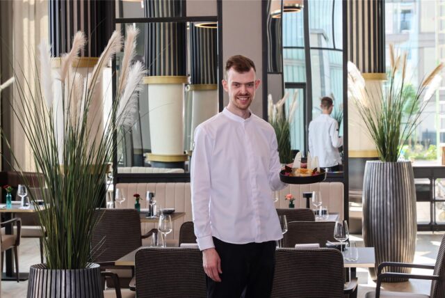 Ein Koch des Dortmunder Restaurants Haus Phönixsee steht im mit einem Teller Essen im Gastraum