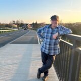 Peter Schwab steht auf der Lippebrücke vor Ahsen, mit dem Dorf im Hintergrund.