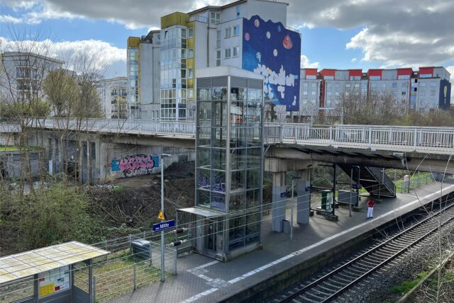 Blick von oben auf den Bahnsteig des Haltepunktes Marl-Mitte. Im Hintergrund sieht man die Rundbebauung der Planetensiedlung.