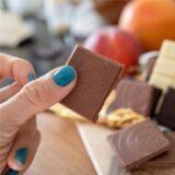 Eine Frau hält ein Stück Schokolade in der Hand.