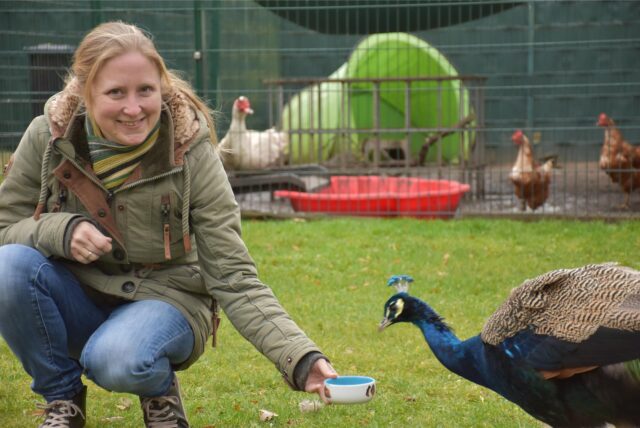 Marina Hinz auf der Wiese des Dorstener Tierheims mit einem Pfau