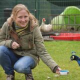 Marina Hinz auf der Wiese des Dorstener Tierheims mit einem Pfau