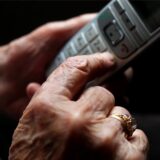 Eine ältere Frau tippt auf einem schnurlosen Festnetztelefon.