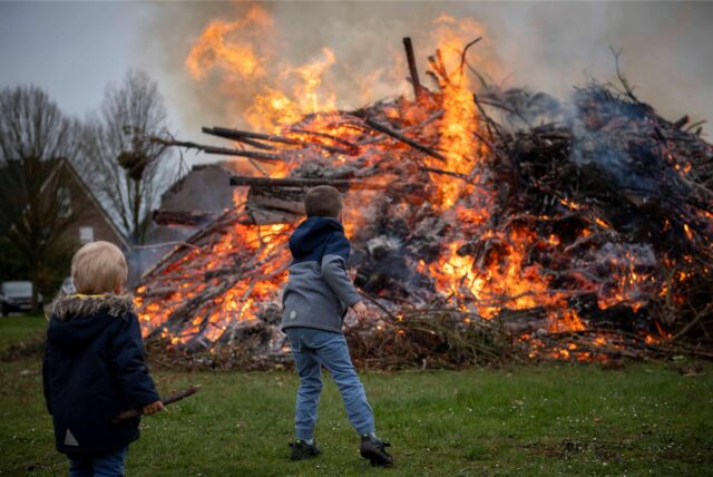 Kinder werfen Holz auf ein Osterfeuer.