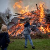 Kinder werfen Holz auf ein Osterfeuer.