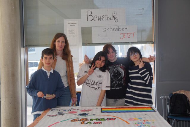 Eine Lehrerin mit drei Schülerinnen und einem Schüler.