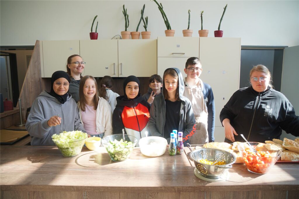 Kinder schauen in die Kamera, vor ihnen steht Essen.