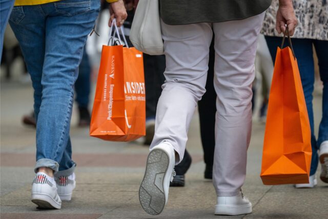 Menschen mit vollen Einkaufstaschen gehen am verkaufsoffenen Sonntag shoppen.