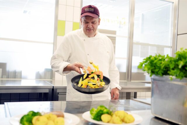 Ingo Grottke von Rebional steht in der Großküche in Herdecke und schwenkt eine Pfanne mit buntem Gemüse.