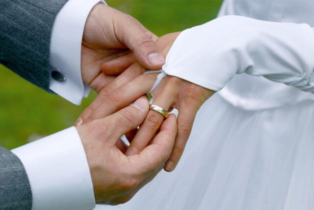 Der Bräutigam steckt seiner Braut den Ehering an den Ringfinger.