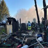 Einsatzkräfte der Feuerwehr stehen zwischen den heruntergebrannten Überresten von Gartenlauben in Dortmund-Menglinghausen.