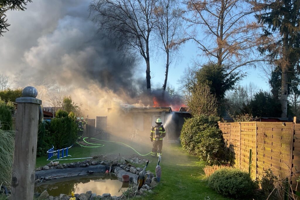Ein Feuerwehrmann löscht eine brennende Gartenlaube in Dortmund-Menglinghausen Ein Feuerwehrmann löscht eine brennende Gartenlaube in Dortmund-Menglinghausen