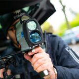 Ein Polizist kontrolliert während des Blitzermarathons mit einem Messgerät die Geschwindigkeit von Fahrzeugen in einer 30er-Zone.