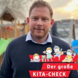 Ein Kita-Vater aus Dortmund steht in seinem Garten. Hinter ihm zu erkennen: eine Rutsche und eine Schaukel.