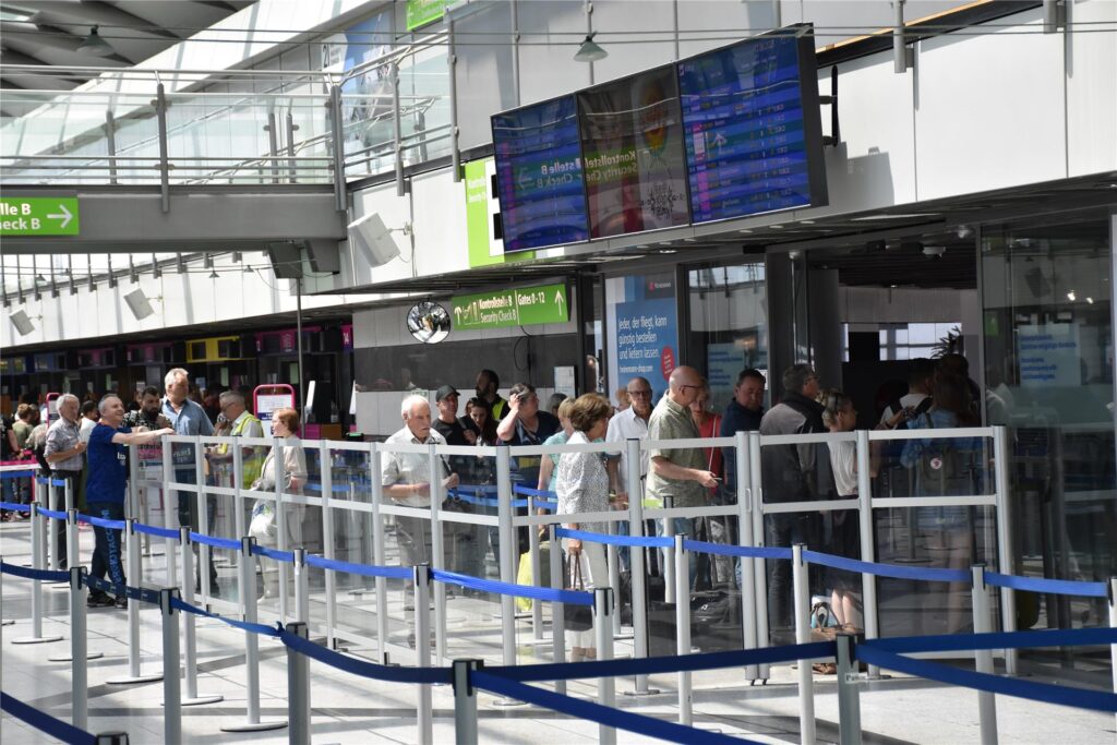 Menschen stehen in der Schlange der Sicherheitskontrolle im Dortmunder Flughafen. Menschen stehen in der Schlange der Sicherheitskontrolle im Dortmunder Flughafen.