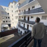 Rainer S. steht im 1. Stock des Wohnhauses und schaut auf die gegenüberliegenden Wohnungen.